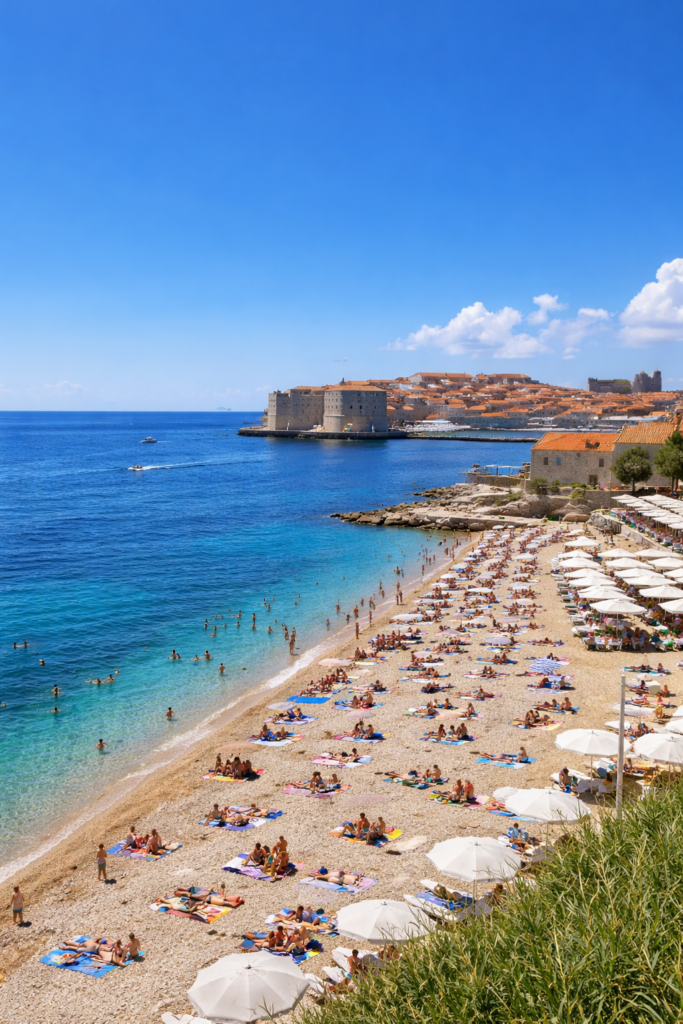 Banje Beach in Dubrovnik with Old Town city walls and Adriatic Sea on a sunny summer day