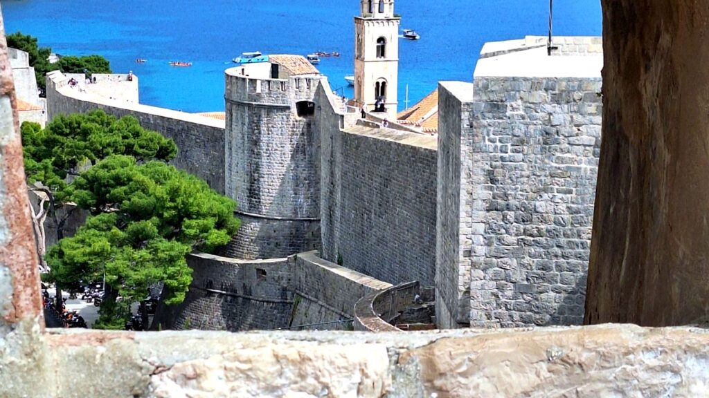 View of Dubrovnik city walls and bell tower framed through a stone window overlooking the Adriatic Sea