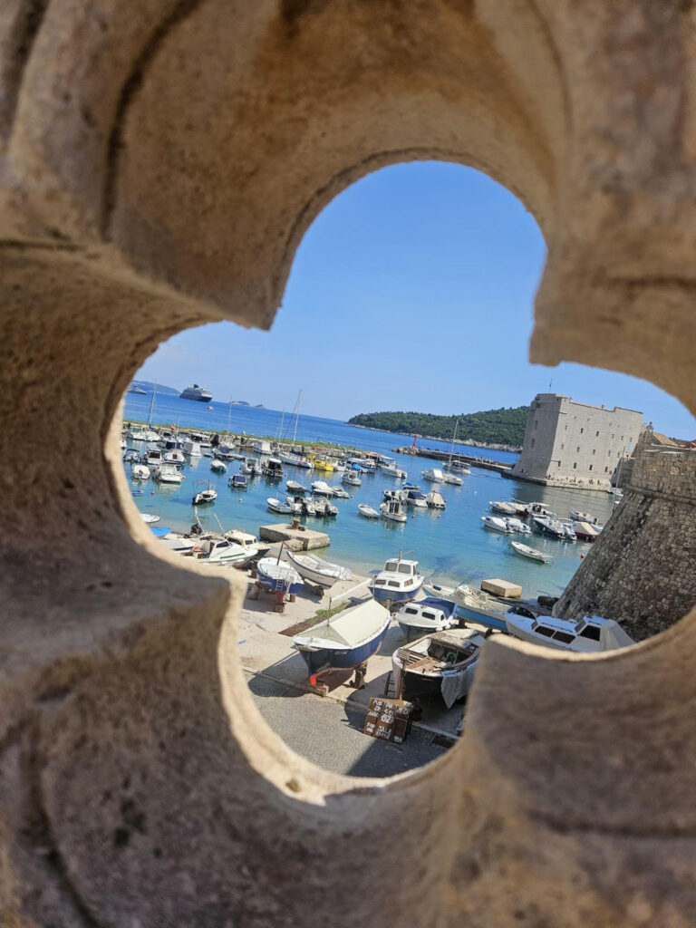 View of Dubrovnik Old Harbor and St. John Fortress through a stone opening in the city walls