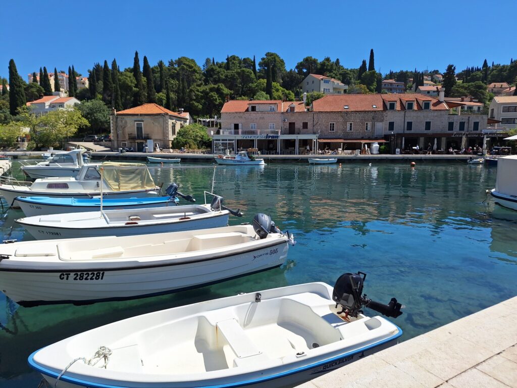 Small boats in Cavtat harbor with clear Adriatic water and waterfront restaurants near Dubrovnik during a private shore excursion