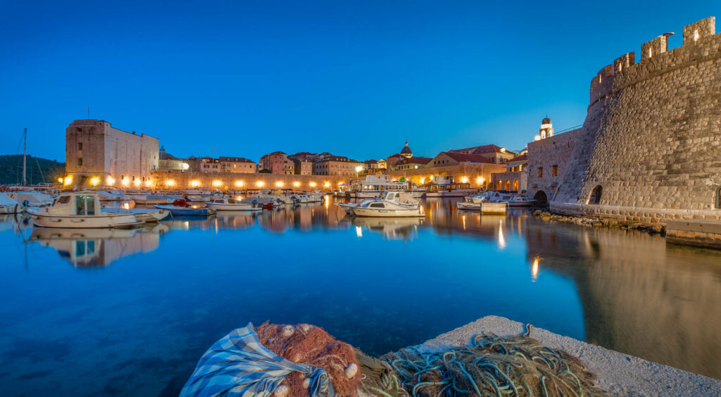 Luxury Dubrovnik travel experience at Old Port during blue hour with calm water, historic city walls, and peaceful atmosphere