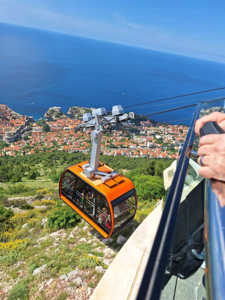 Dubrovnik Cable Car descending from Mount Srđ with panoramic views of Dubrovnik Old Town, the Adriatic Sea, and the surrounding coastline.