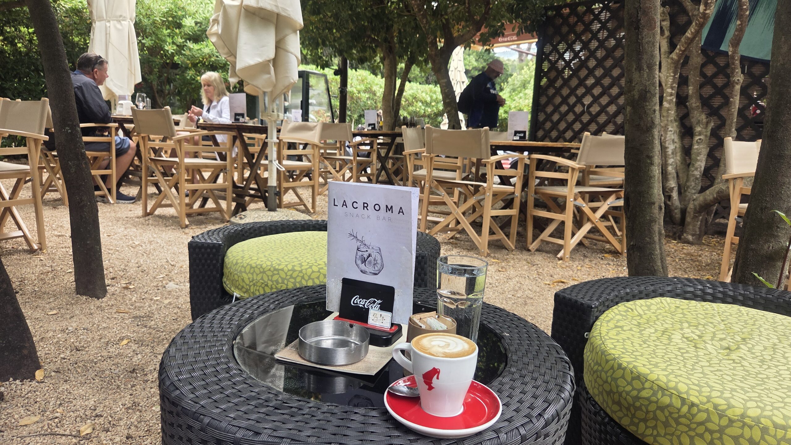 Relaxing outdoor coffee garden in Dubrovnik where locals enjoy slow Mediterranean lifestyle surrounded by greenery and shade trees