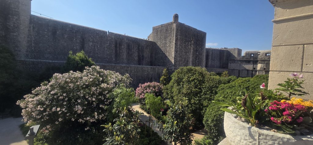 Historic Dubrovnik city walls overlooking a peaceful garden inside the Old Town.