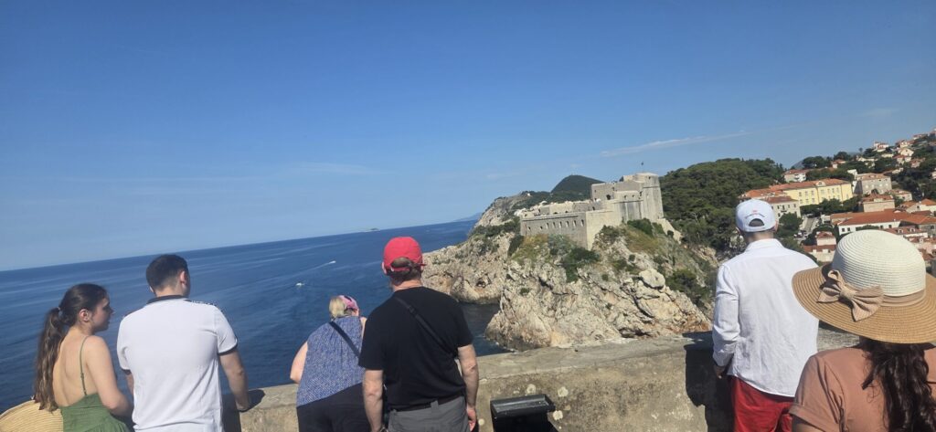 Visitors enjoying panoramic views of Fort Lovrijenac and the Adriatic Sea from Dubrovnik's historic city walls.