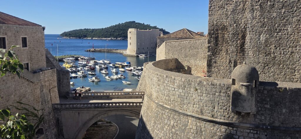 Dubrovnik Old Port with historic stone fortifications, boats, Fort St. John, and Lokrum Island in the background