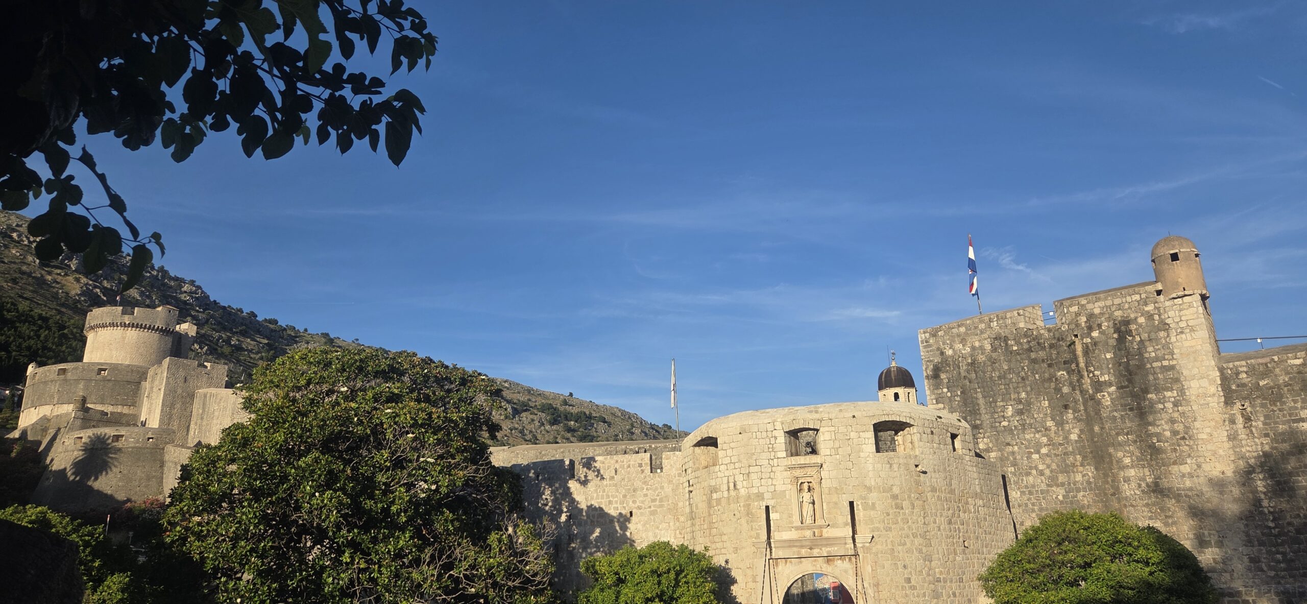 Historic Dubrovnik city walls and Pile Gate entrance illuminated by morning sunlight