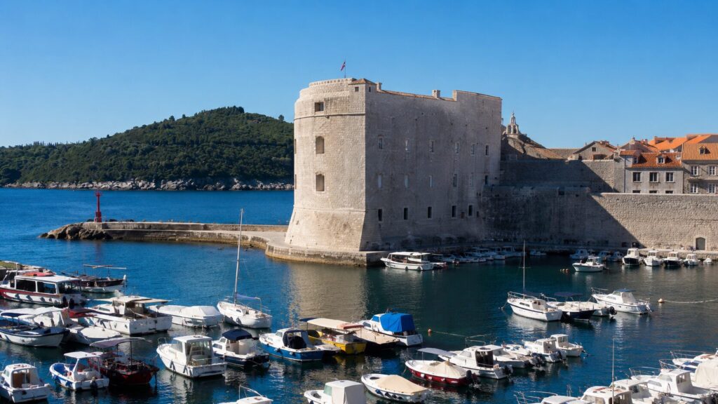 Fort St. John in Dubrovnik Old Port, with stone harbor walls, small boats, and Lokrum Island in the background