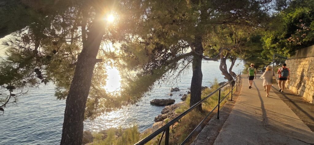 Visitors walking along Cavtat’s pine-lined coastal path at sunset in one of my photographs