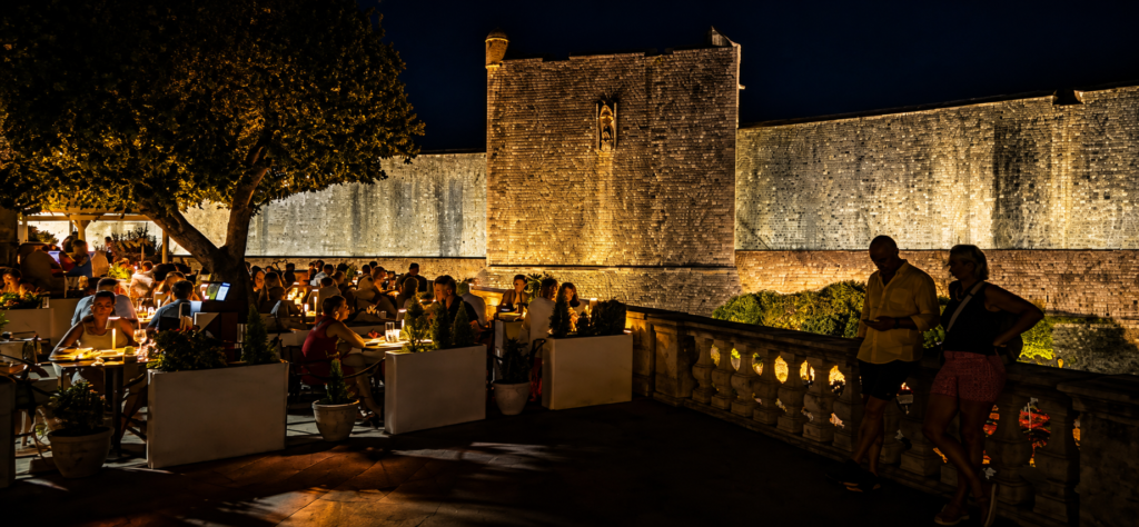 Dubravka restaurant terrace at night beside the illuminated Dubrovnik City Walls