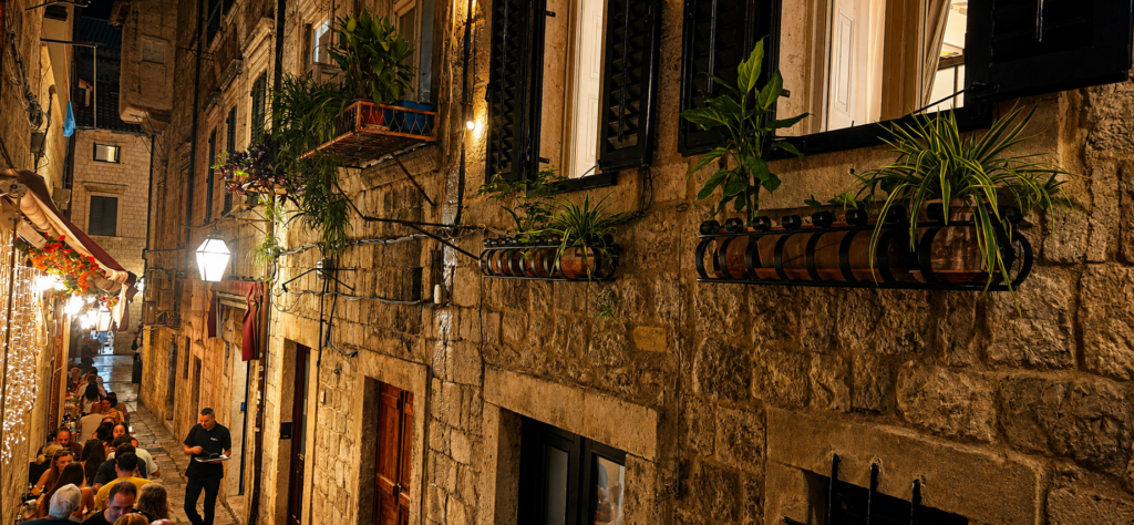 Narrow side street in Dubrovnik Old Town at night with restaurant tables and stone houses