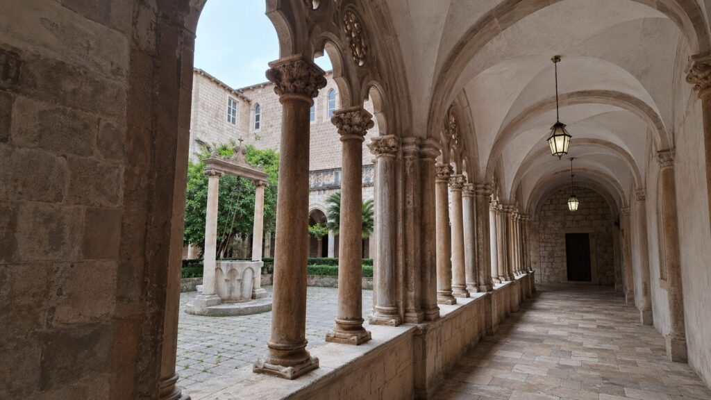 Franciscan Monastery cloister in Dubrovnik with carved stone columns, vaulted arches and the historic courtyard well.