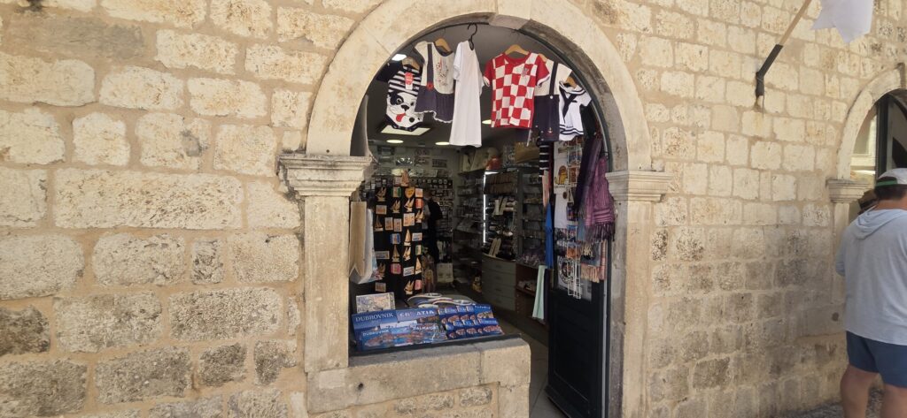 Souvenir shop on Stradun in Dubrovnik displaying Croatia national football shirts, magnets, postcards and other gifts.