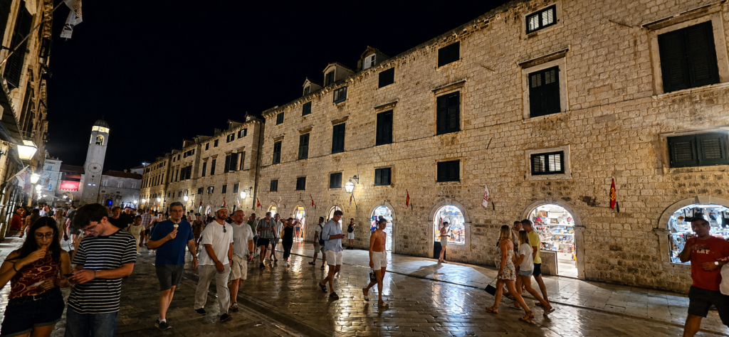 Stradun in Dubrovnik at night with illuminated stone buildings and evening crowds