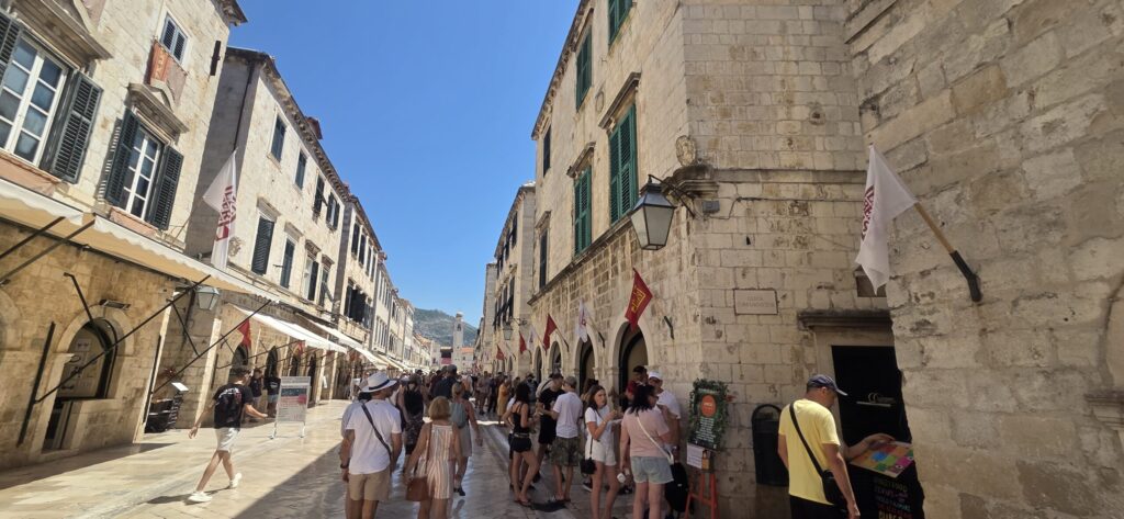 Uniform stone façades and traditional shopfronts along Stradun in Dubrovnik, showing the street’s post-1667 architectural design.